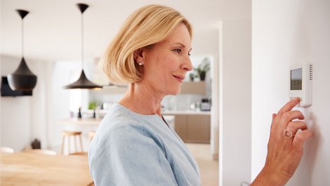 Heizkosten senken, eine Frau gibt an einem digitalen Thermostat die Temperatur ein, Foto: Monkey Business/stock.adobe.com