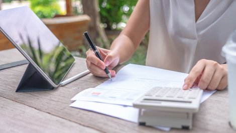 Heizkosten abrechnen, Frau rechnet Werte auf einem Dokument nach, Foto: zasabe / stock.adobe.com