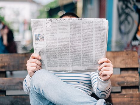 Wettbewerbsrecht, Makler, verschleierte Werbung, ein Mann auf einer Bank liest Zeitung, Foto: Roman Kraft / Unsplash