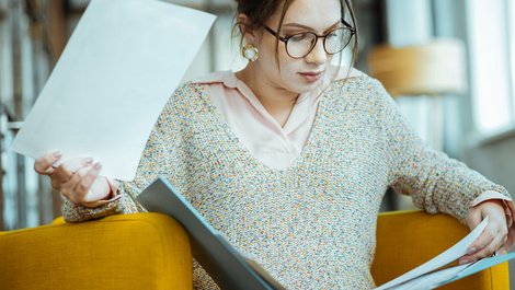 Heizkostenabrechnung prüfen, Frau sieht sich Dokumente in einem Ordner an, Foto: zinkevych / stock.adobe.com