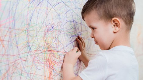 Ausmalen beim Auszug, ein Foto mit einem kleinen Jungen, der eine weiße Wand mit Buntstiften anmalt, Foto: iStock.com / JohnAlexandr